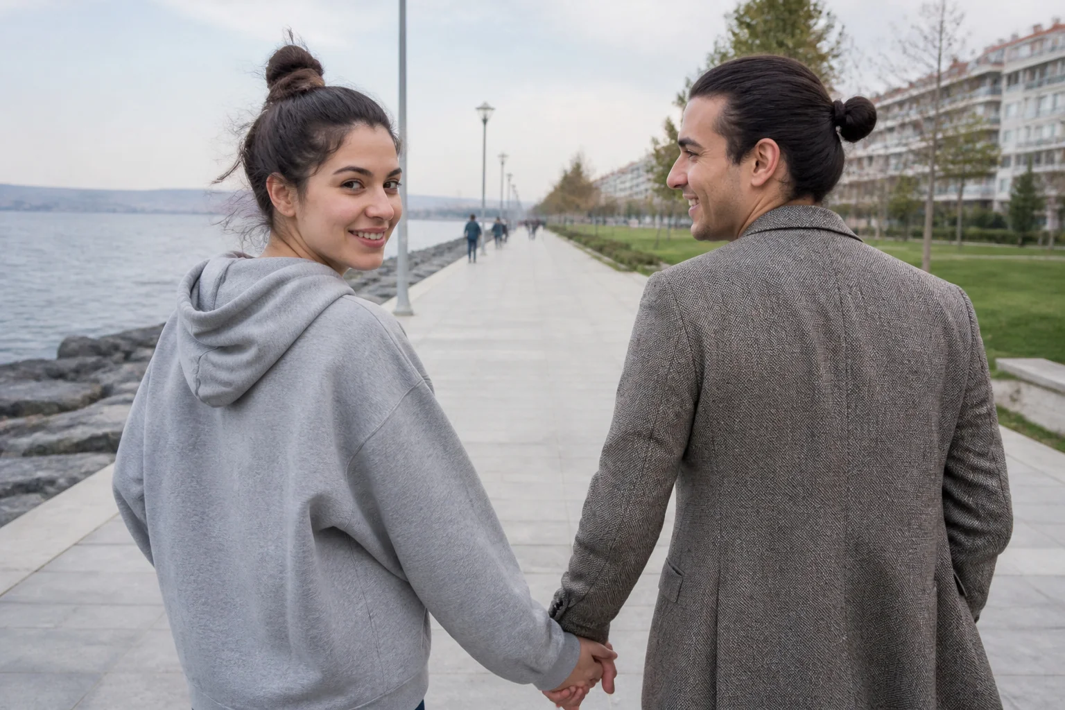 Deniz kenarındaki yürüyüş yolunda el ele yürüyen genç bir çift